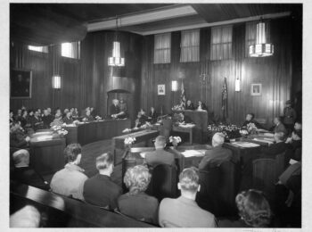 Council chambers during a meeting in progress, 1949. The City Clerk is at the desk in front of the Mayor, taking the minutes. Reference code: COV-S62-: CVA 296-350